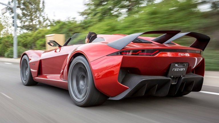 A Rezvani Beast sports car drives down the road with its top down.