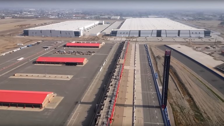This aerial image depicts two new warehouses visible in the background of the remains of NASCAR's Auto Club Speedway near Fontana, California.